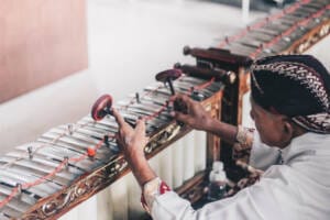 Illustrasi orang yang menikmati pertunjukan gamelan tradisional, memperlihatkan keberlimpahan warisan budaya Yogyakarta di tahun 2023.