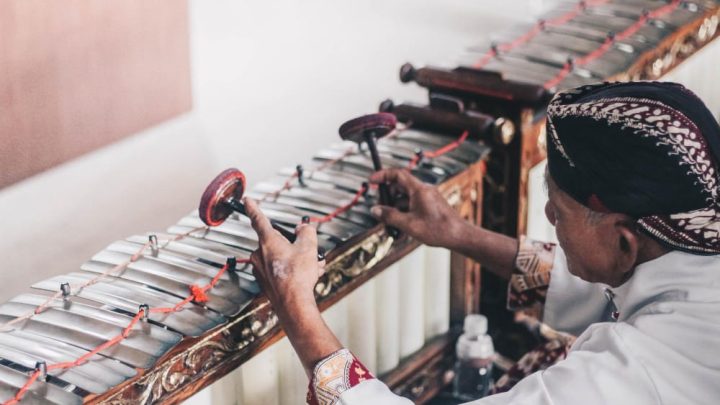 Illustrasi orang yang menikmati pertunjukan gamelan tradisional, memperlihatkan keberlimpahan warisan budaya Yogyakarta di tahun 2023.