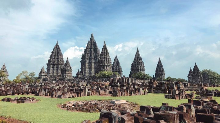 Aerial view of Prambanan Temple complex with intricate stone carvings against a backdrop of lush greenery.
